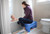 Mom sitting on the Periwinkle Sibling Step Stool during bath time